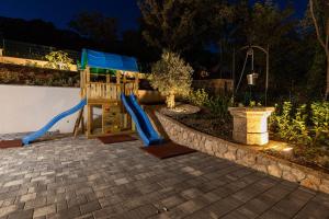ein Spielplatz mit einer Rutsche in einem Hof bei Nacht in der Unterkunft Vila Petram in Bribir