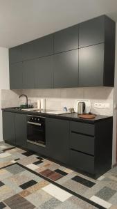 a kitchen with black cabinets and a stove at Apartament Włoski Styl in Gniezno