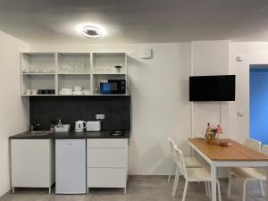 Apartmán Doma na Lipně في ليبنو ناد فلتافو: مطبخ بدولاب بيضاء وطاولة وتلفزيون