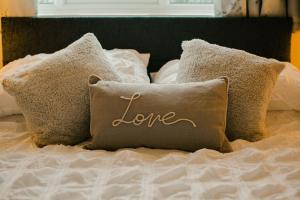 a pillow with the word love written on it on a bed at Granary at Tyddyn Isaf in Ruthin