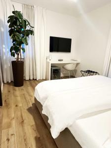 a white bedroom with a bed and a tv at Garni Hotello Sport And Relax in Riva del Garda