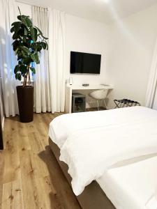 a white bedroom with a bed and a tv at SK Active hotel - ex Garni Hotello in Riva del Garda
