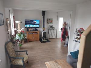 a living room with a tv and a wooden floor at Une chambre presque en ville in Quimper