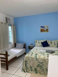 a bedroom with a bed and a blue wall at Caminho das Pedras Búzios in Búzios