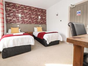 two beds in a room with a desk and a table at The Red Well Country Inn in Carnforth