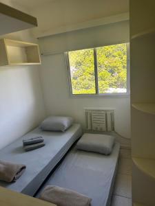 two beds in a small room with a window at Barra da Tijuca Rio centro in Rio de Janeiro