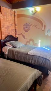 1 dormitorio con 2 camas y una pared con un mural en Alondra Posada Turística, escape con chimenea a una hora de Bogotá, en Sesquilé