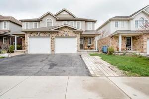 a house with two white garage doors in a driveway at Nimo Homestay in Guelph