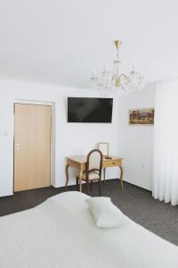 1 dormitorio con cama, mesa y lámpara de araña en Penzion Jakub, en Lanškroun