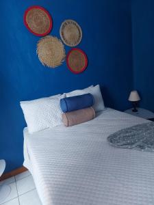 Dormitorio azul con cama blanca con cestas en la pared en Casa familiar La Arboleda en Guatemala