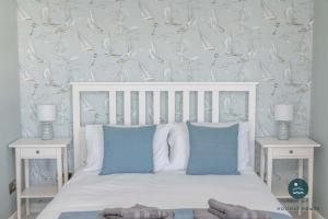 a bedroom with a white bed with blue pillows at Comfort Hill - Luxury hot tub sea views in Overcombe