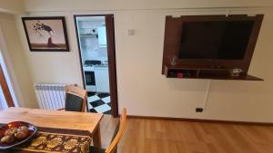 uma sala de jantar com uma mesa e uma televisão na parede em Apartamento Urquiza em San Carlos de Bariloche