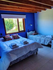 niebieska sypialnia z 2 łóżkami i oknem w obiekcie My home 2 w mieście El Calafate
