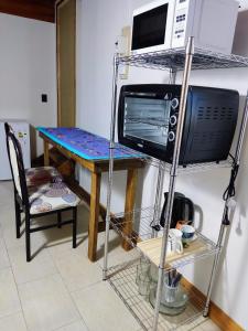 Pokój z biurkiem, kuchenką mikrofalową i stołem w obiekcie My home 2 w mieście El Calafate