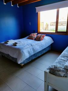 Dormitorio azul con cama y ventana en My home 2 en El Calafate