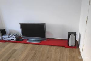TV sentada en una mesa roja en una habitación en Precioso apartamento con magnífico patio. en Sant Feliu de Llobregat