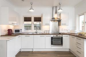 una cocina blanca con armarios y electrodomésticos blancos en London House en Londres