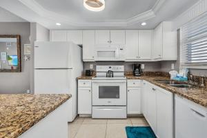 フォートマイヤーズビーチにあるWelcome to Beach Villa's # 602 Vacation Rental - 250 Estero Blvd condoの白いキャビネットと白い冷蔵庫のあるキッチン