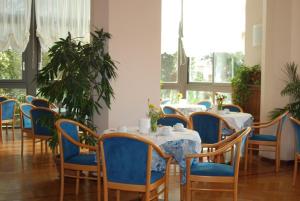 a dining room with tables and blue chairs and windows at Hotel Napoleon in Sanremo