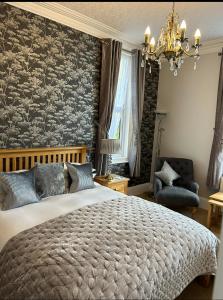 a bedroom with a large bed and a chandelier at Elmdene in Torquay