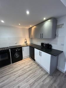 uma cozinha com armários brancos e um balcão preto em Hertford HOME em Hertford