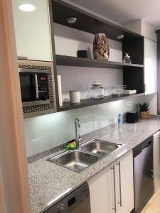 cocina con fregadero y microondas en Apartamentos Oasis, en Albir