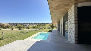 an external view of a house with a swimming pool at Casa Pit - Casa en chapa con pileta Barrio Privado 6PX I Hola Sur in Mar del Plata