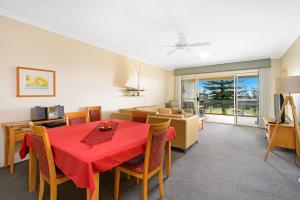 a dining room with a red table and chairs at Harbourwatch 11 18 Burrawan Street in Port Macquarie