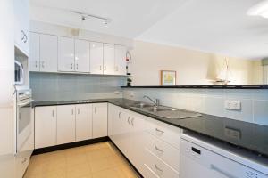eine weiße Küche mit weißen Schränken und einer Spüle in der Unterkunft Harbourwatch 11 18 Burrawan Street in Port Macquarie + 4 Fotos