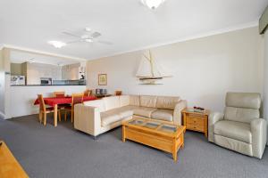 ein Wohnzimmer mit Sofa und Tisch in der Unterkunft Harbourwatch 11 18 Burrawan Street in Port Macquarie