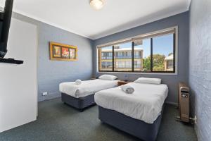 a room with two beds and a window at Alpine Mountain View 18 - 4BR l Mountain Views l Swimming Pool l Air-Con l WiFi in Jindabyne