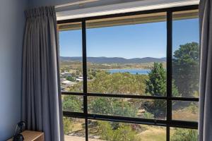 a room with a window with a view of a lake at Alpine Mountain View 18 - 4BR l Mountain Views l Swimming Pool l Air-Con l WiFi in Jindabyne