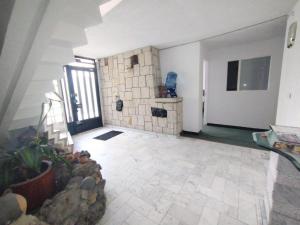 a living room with a stone wall and a tile floor at Innovar Casa Hostal in Bogotá