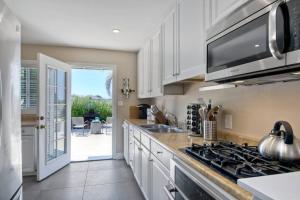a kitchen with white cabinets and a stove top oven at Ocean View Spa Retreat, Hot Tub, Sauna, Close to the beach, 9 sleeps in Oceanside