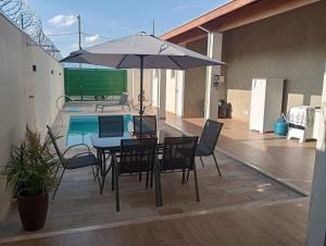 a patio with a table and umbrella next to a pool at Espaço Cris in Pindamonhangaba