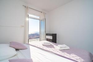 a white bedroom with a bed and a window at Isaura Apartments in Dubrovnik