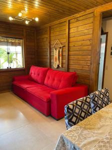 czerwona kanapa w pokoju z drewnianymi ścianami w obiekcie Millicent Residence - Chalet Milly e Chalet Iris - Itaoca Praia - ES w mieście Itapemirim