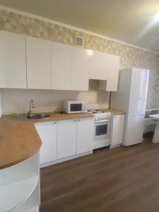 Комфортабельные - Уютные квартиры в городе Костанай (Плаза) في كوستاناي: مطبخ بخزائن بيضاء ومغسلة وثلاجة