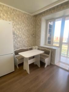 Комфортабельные - Уютные квартиры в городе Костанай (Плаза) في كوستاناي: غرفة معيشة مع طاولة بيضاء وأريكة +3 صور