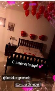 een slaapkamer met een bed met rode ballonnen aan de muur bij Flat Deluxe Gramado in Gramado