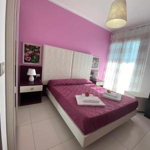 a purple bedroom with a bed with two towels on it at B&B La Perla in Racale