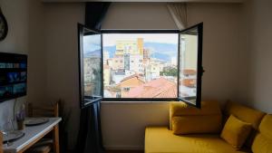 una finestra in una camera con divano giallo e vista di 2E Center Apartment a Tirana