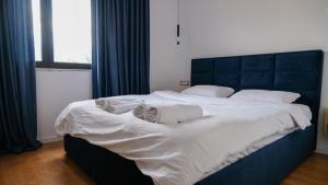 un grande letto con lenzuola bianche e asciugamani sopra di 2E Center Apartment a Tirana