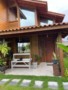 una casa de madera con un banco en el patio en Millicent Residence - Chalet Milly e Chalet Iris - Itaoca Praia - ES, en Itapemirim