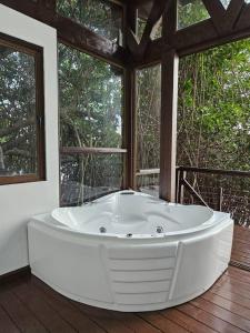 una gran bañera blanca en una habitación con ventanas en Willo's Treehouse, en Escuintla