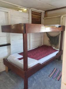 Litera de madera en una habitación pequeña en Schmidt’s Natures Way Guesthouse, en Punta Gorda