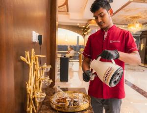 um homem de camisa vermelha segurando um liquidificador em Areen Hotel em Jeddah