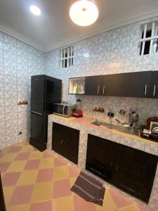 a kitchen with black appliances and a checkered floor at Charly Cabanadeluxe in Cotonou