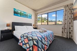 a bedroom with a bed and a large window at Alpine Mountain View 39 Ground Floor 3 Bedroom Unit in Jindabyne