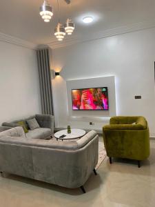 a living room with a couch and two chairs and a tv at Charly Cabanadeluxe in Cotonou